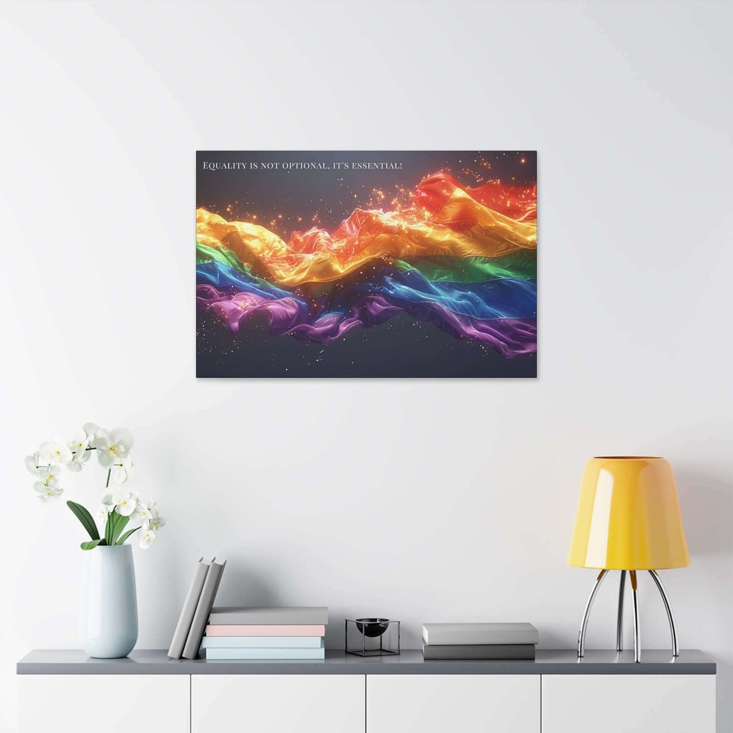 A vibrant, flowing ribbon in the colors of the rainbow, resembling the LGBTQ+ pride flag, stretches across a dark background with sparks and light effects. The "Essential Equality: Radiant Gay Pride Canvas Wall Art" by Printify features text at the top that reads, "Equality for the LGBTQ+ community is not optional, it's essential!