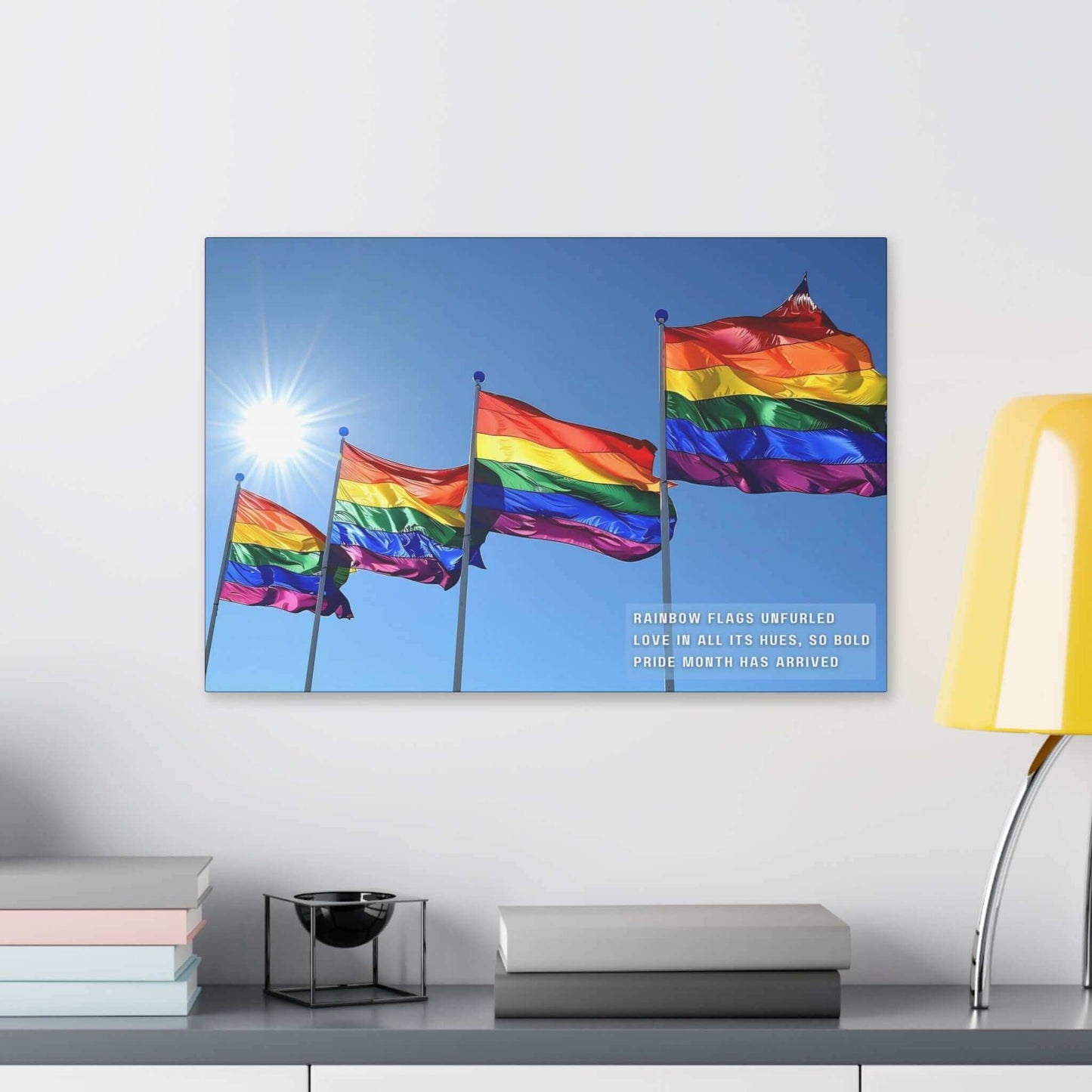 A collection of Bold Rainbow Flags Canvas Wall Art from Printify is shown flying in the breeze against a clear blue sky, with sunlight shining brightly in the background. The text on the vibrant Pride Month Art Print reads, "RAINBOW FLAGS UNFURLED LOVE IN ALL ITS HUES, SO BOLD PRIDE MONTH HAS ARRIVED," celebrating the LGBTQ+ community.