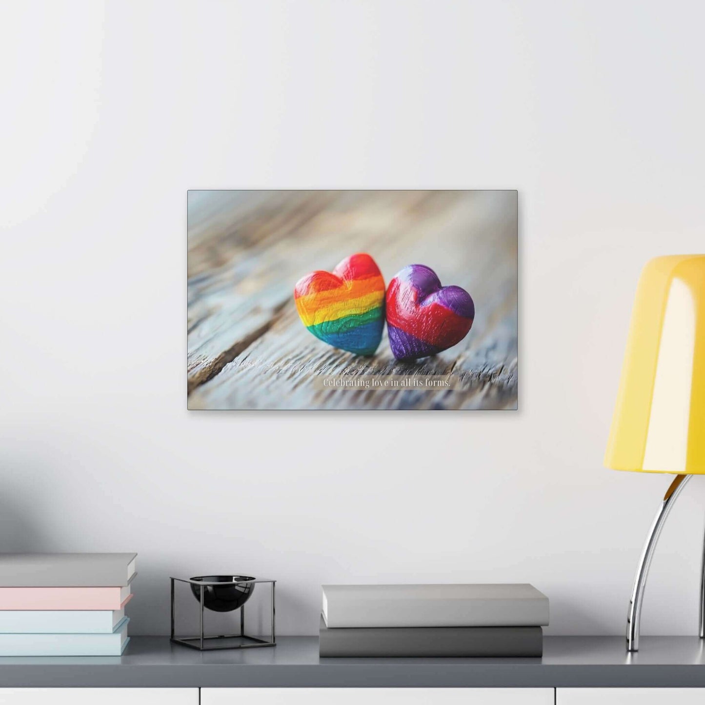 Two heart-shaped stones rest on a wooden surface. One heart features vibrant rainbow colors, while the other displays enchanting shades of purple. Overlayed text reads, "Celebrating love in all its forms." The image emanates a message of love and inclusivity, honoring diverse love within the LGBTQ+ community with Printify's "Love in All Forms: Beautiful Gay Pride Canvas Wall Art, Inspired by Heartfelt 6-Word Story | PR-6W-007c.