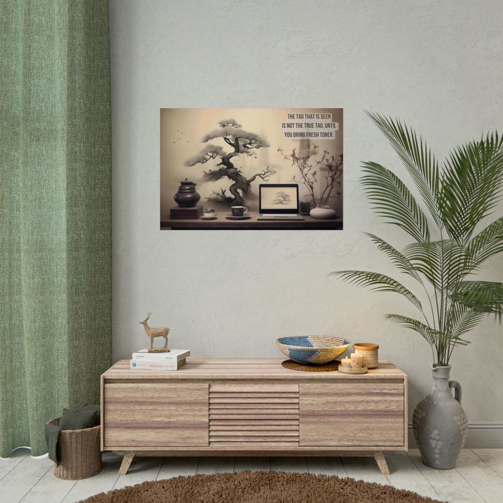 A workspace includes a laptop, a cup, a teapot, a stack of books, and a plant. An Asian-Inspired Poster Wall Art with Bonsai & Clever Haiku by Printify blends seamlessly with the real objects. The humorous Asian-themed text reads, "The Tao that is seen is not the true Tao, until you bring fresh toner.