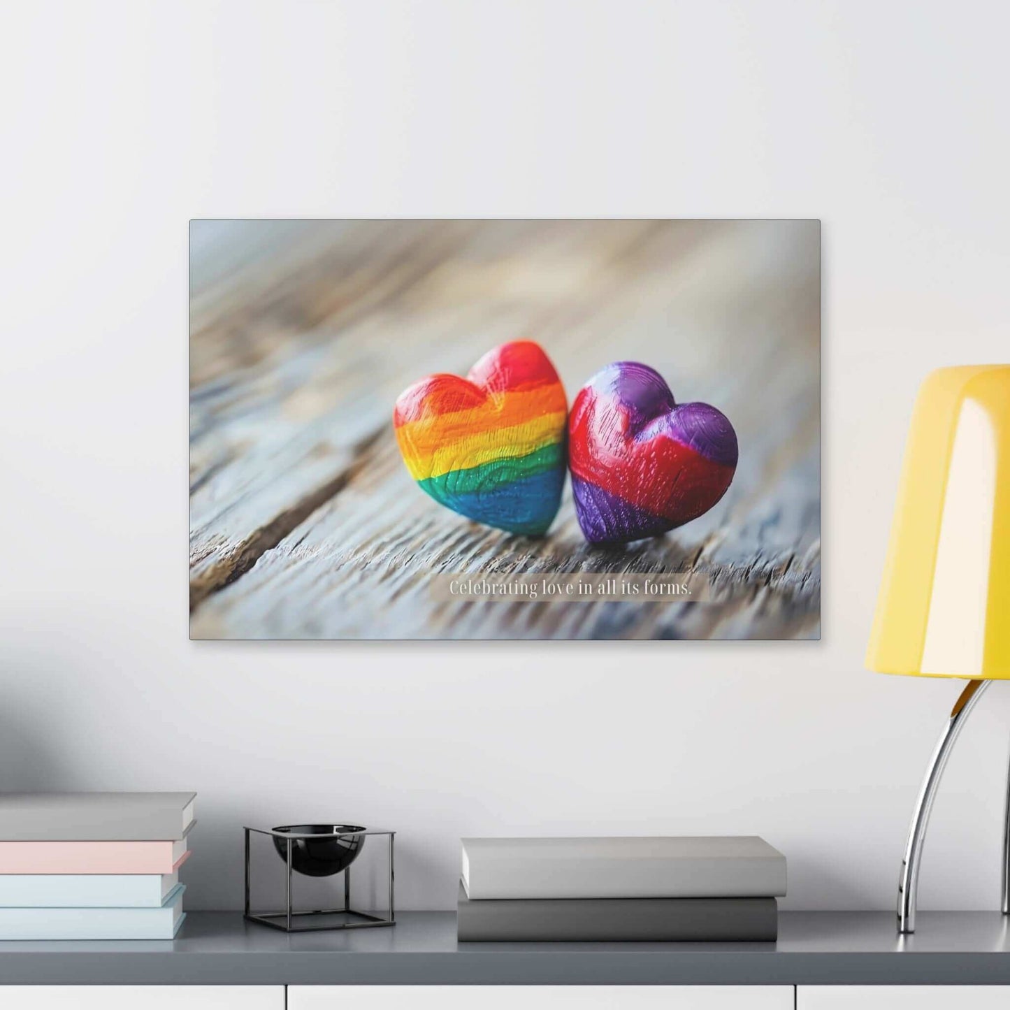 Two heart-shaped stones rest on a wooden surface. One heart features vibrant rainbow colors, while the other displays enchanting shades of purple. Overlayed text reads, "Celebrating love in all its forms." The image emanates a message of love and inclusivity, honoring diverse love within the LGBTQ+ community with Printify's "Love in All Forms: Beautiful Gay Pride Canvas Wall Art, Inspired by Heartfelt 6-Word Story | PR-6W-007c.