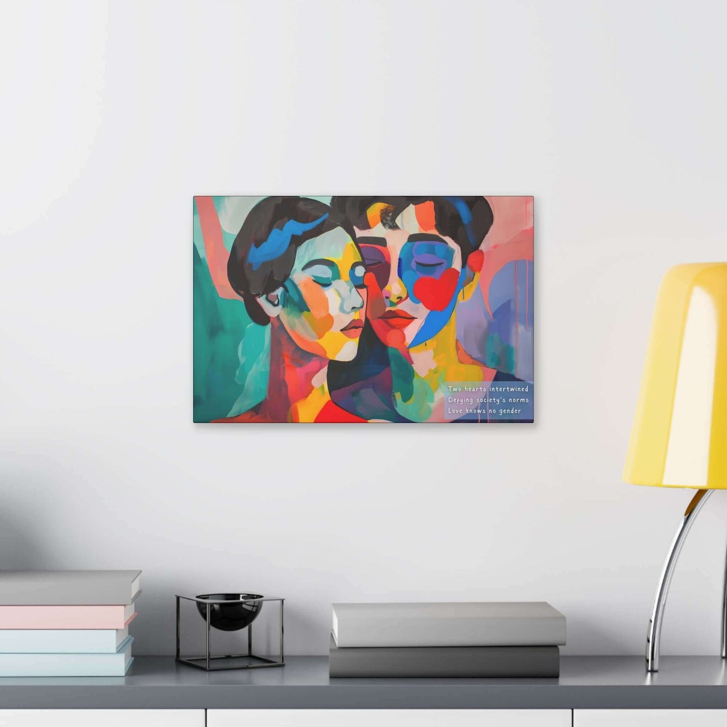 A vibrant and colorful piece titled "Intertwined Love: Vibrant Abstract Couple Canvas Wall Art, Inspired by Empowering Haiku" by Printify showcases two abstract faces with one having closed eyes, leaning towards each other. In the corner, text reads: "Two hearts intertwined defy society’s norms. Love knows no gender." The background features bold, multicolored brushstrokes that highlight inclusivity and abstract representation.