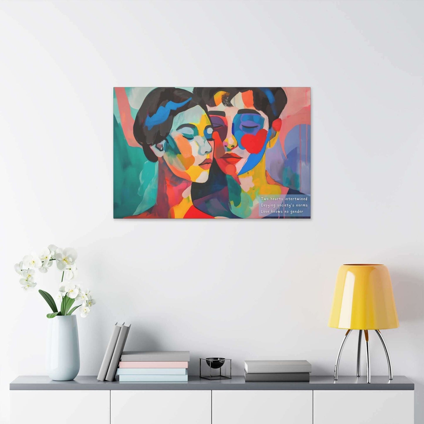 A vibrant and colorful piece titled "Intertwined Love: Vibrant Abstract Couple Canvas Wall Art, Inspired by Empowering Haiku" by Printify showcases two abstract faces with one having closed eyes, leaning towards each other. In the corner, text reads: "Two hearts intertwined defy society’s norms. Love knows no gender." The background features bold, multicolored brushstrokes that highlight inclusivity and abstract representation.